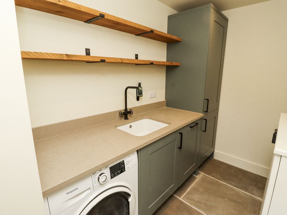 A laundry room with a washing machine and sink at West Dunkirk Hemmels Hexham