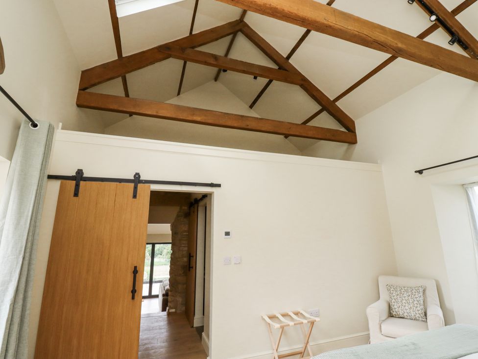 A bedroom with a wooden beam ceiling and a sliding door at West Dunkirk Hemmels in Hexham