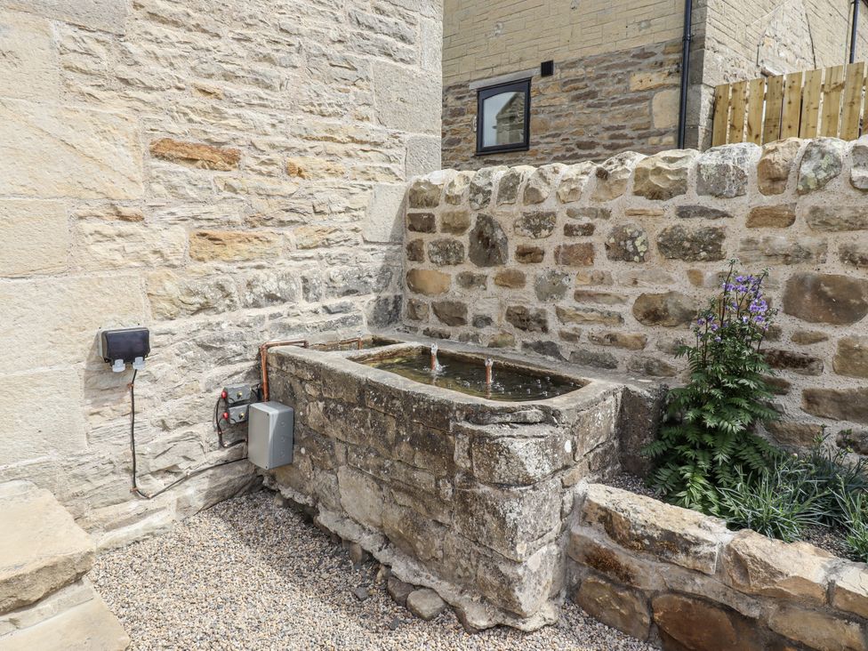 A stone water feature with plants in an outdoor area at West Dunkirk Hemmels Hexham