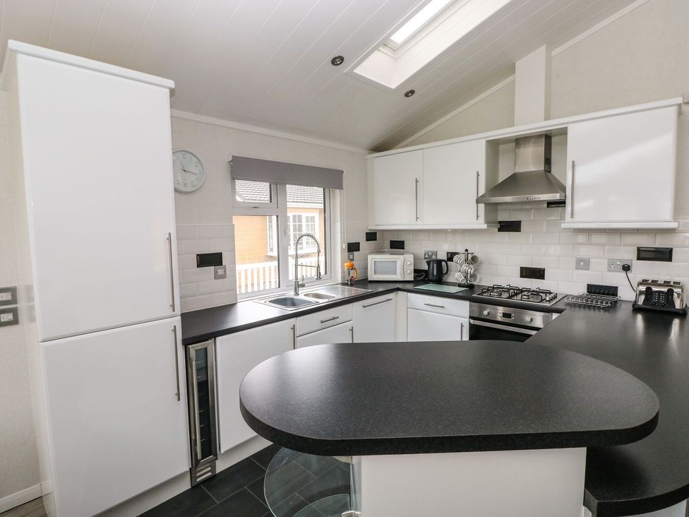 A kitchen with sink, microwave, kettle, and stove at Erisa