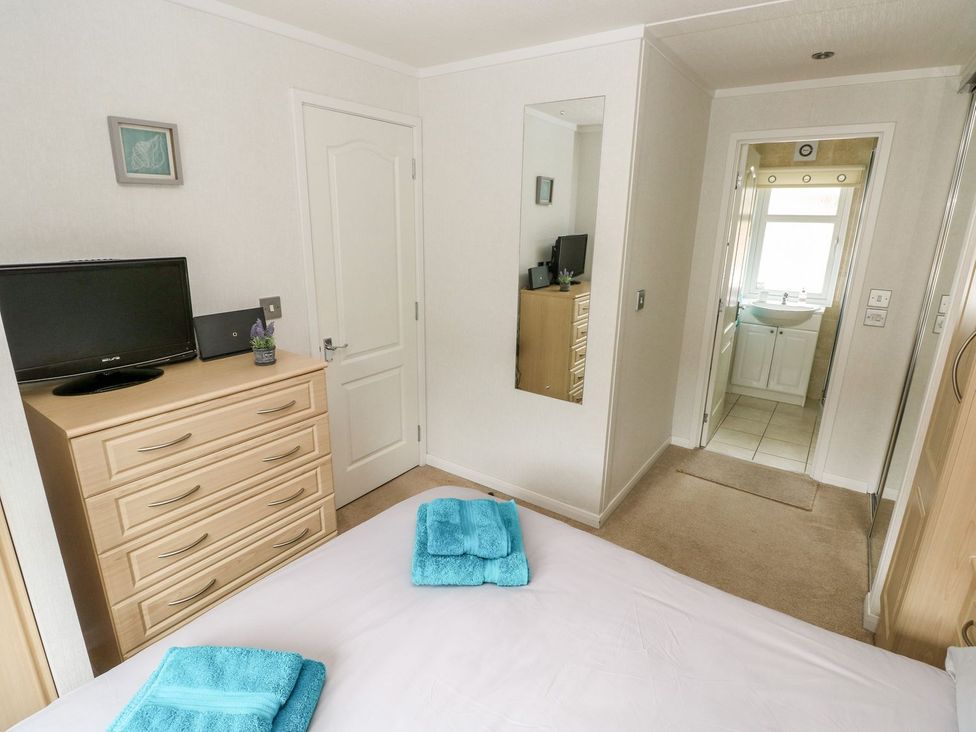 A bedroom with a television and towels on the bed at Erisa