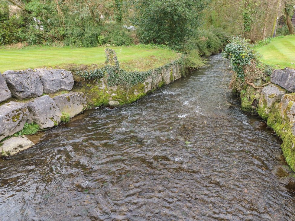 A stream flowing near a stone wall and grassy area at Erisa in Stepaside