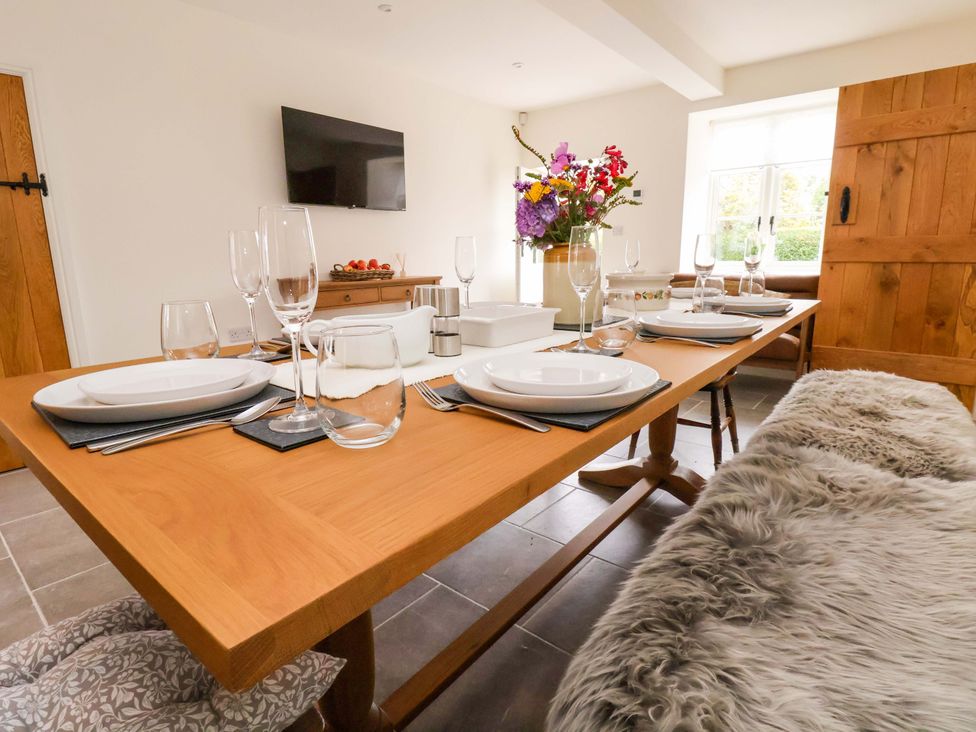 A dining room with a large table and flower arrangement at Isfryn in 