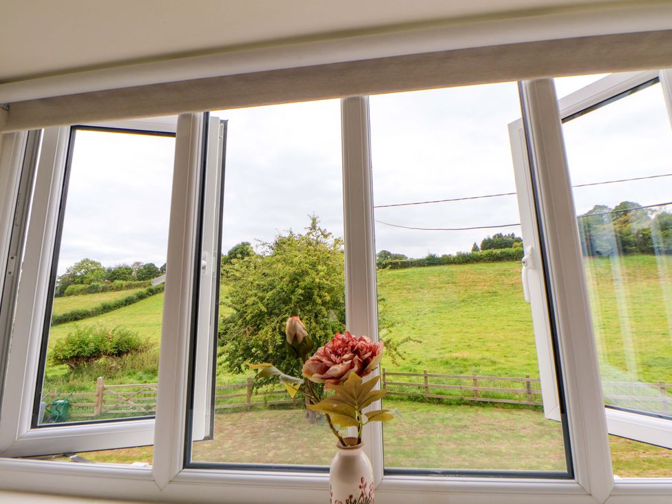 A view of a field through opened windows at Isfryn 