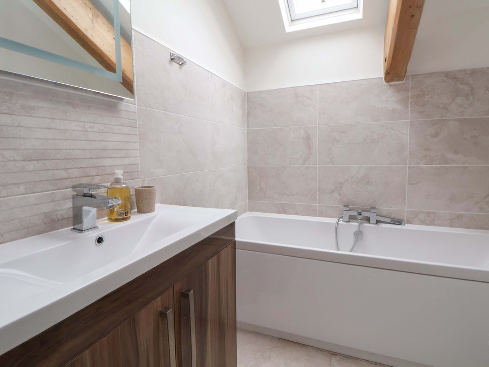 A bathroom with a bathtub and sink at Isfryn