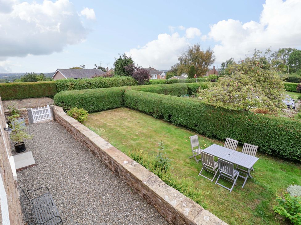 A garden with a table and chairs surrounded by hedges at Isfryn