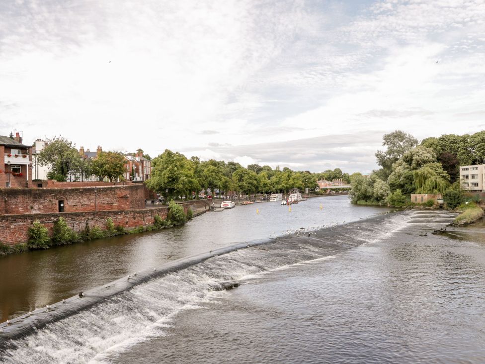 A river with a waterfall and boats along the bank at Isfryn Nercwys