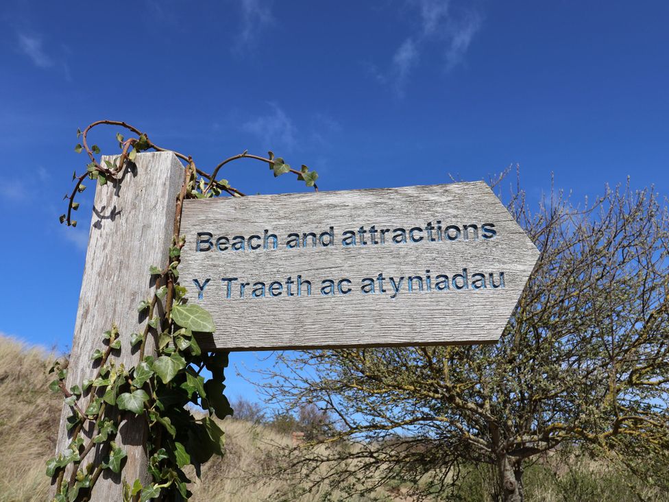 A wooden sign pointing to beach and attractions at Isfryn Nercwys