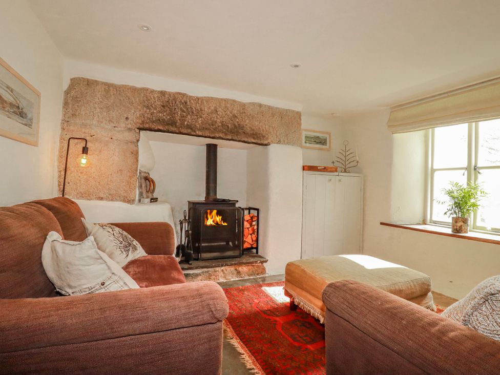 A living room with a fireplace and sofa at Poldue House in Watergate near Camelford