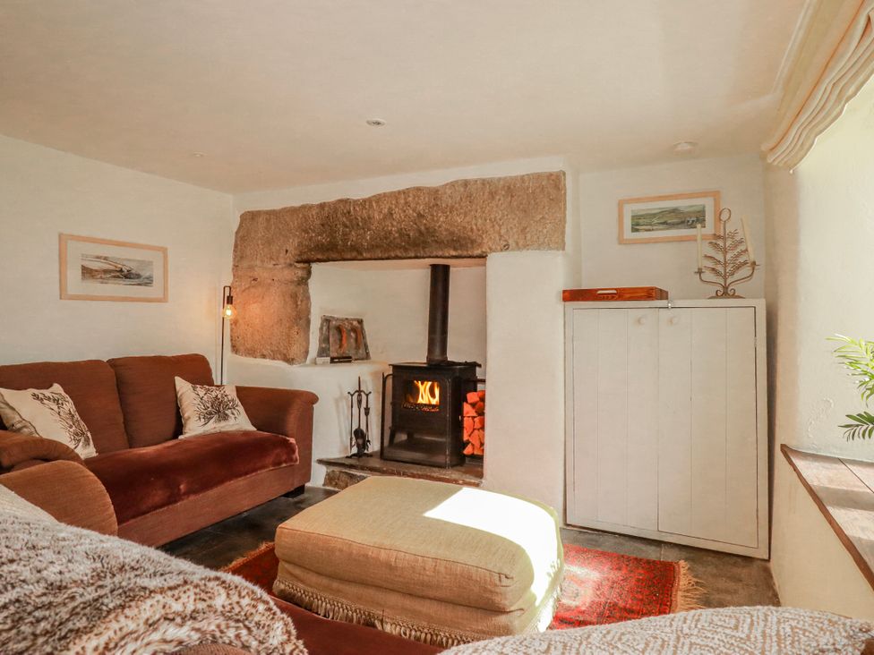 A living room with a fireplace and sofa at Poldue House Watergate near Camelford