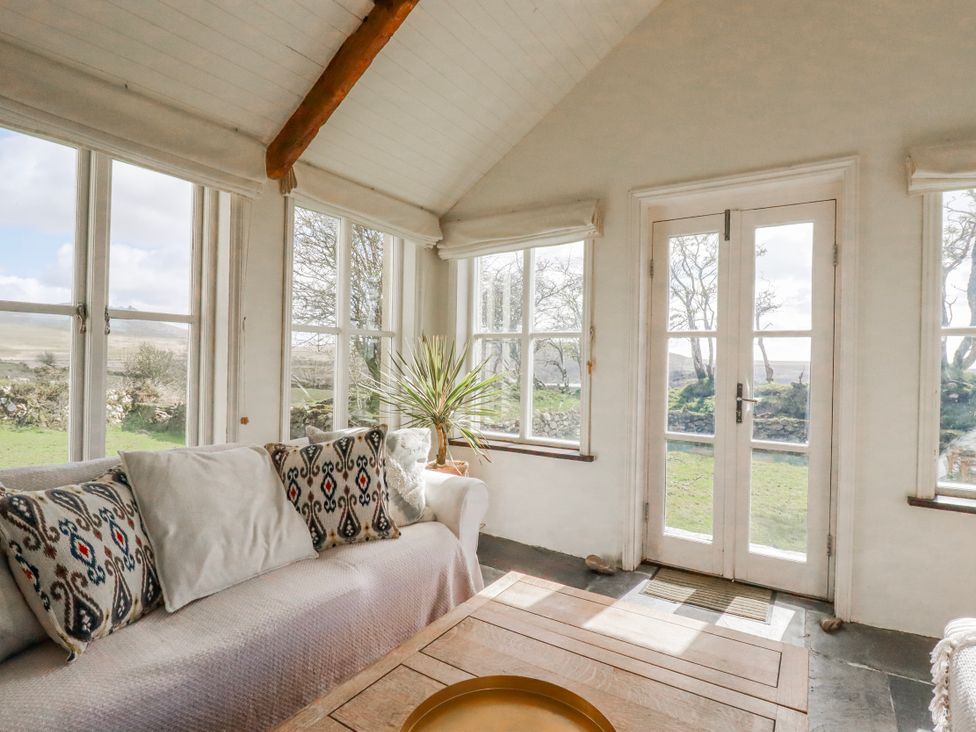 A conservatory with a sofa and coffee table at Poldue House near Camelford