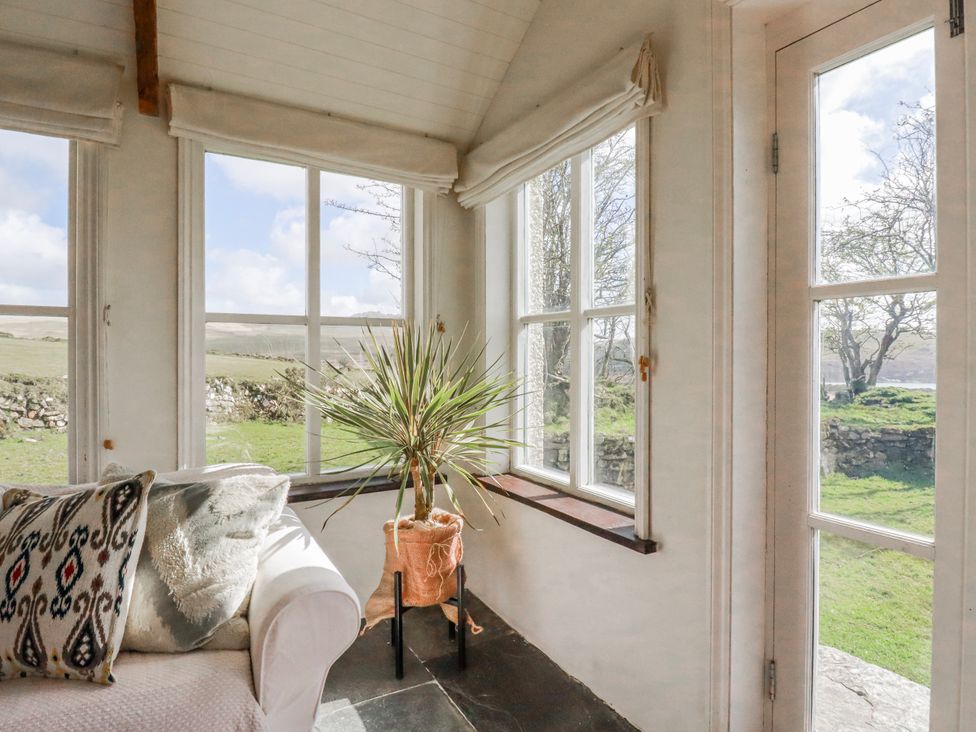 A conservatory with a plant and couch at Poldue House Watergate near Camelford
