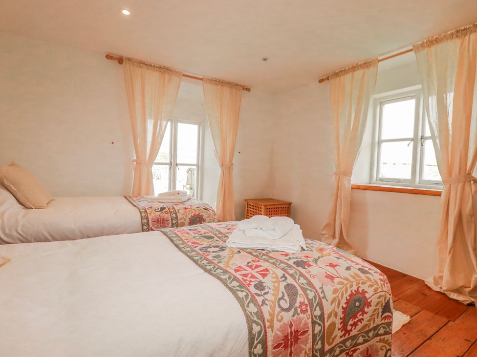 A bedroom with two beds and windows at Poldue House Watergate near Camelford