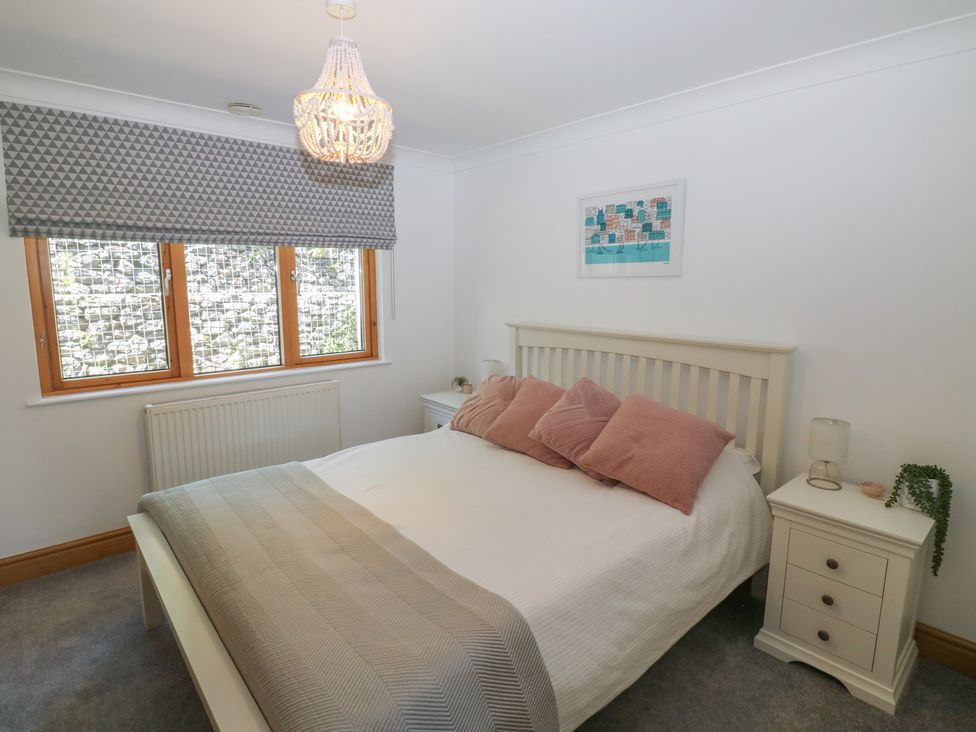 A bedroom with a bed and nightstand at 2 Court Cottage Dartmouth