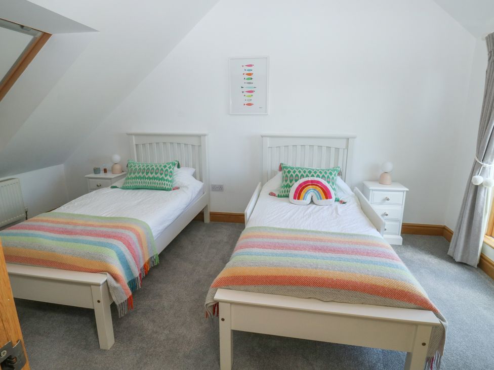 A bedroom with two beds and bedside tables at 2 Court Cottage in Dartmouth