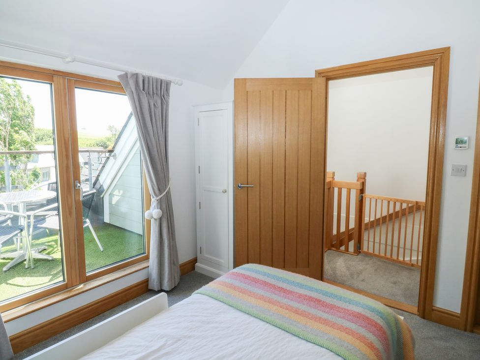 A bedroom with a bed and windows leading to a terrace at 2 Court Cottage Dartmouth