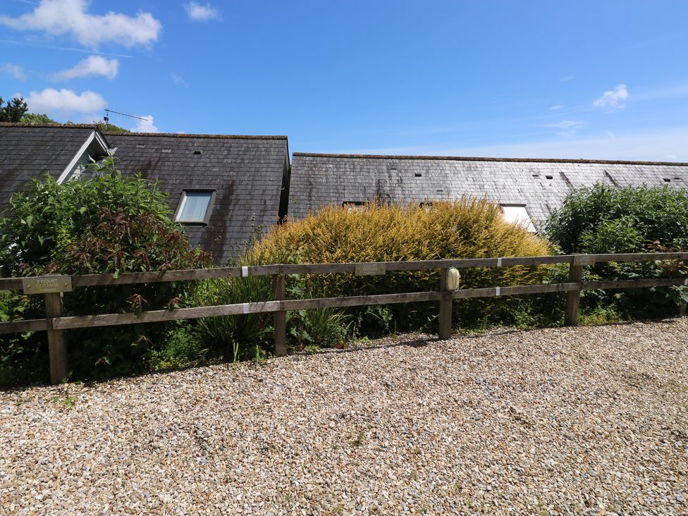 A view of two houses with a gravel area and bushes at 2 Court Cottage in Dartmouth