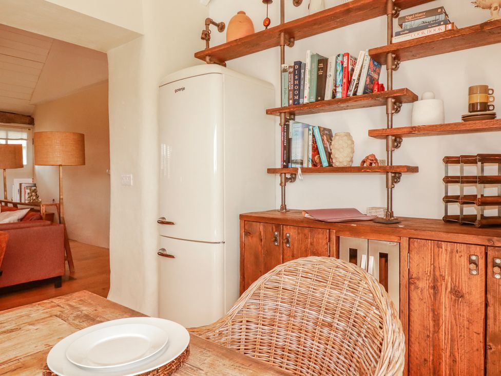 A dining room with a refrigerator and a wooden table at Roughtor Barn Poldue near Camelford
