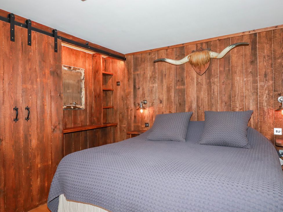 A bedroom with a bed and wooden shelves at Roughtor Barn Poldue near Camelford