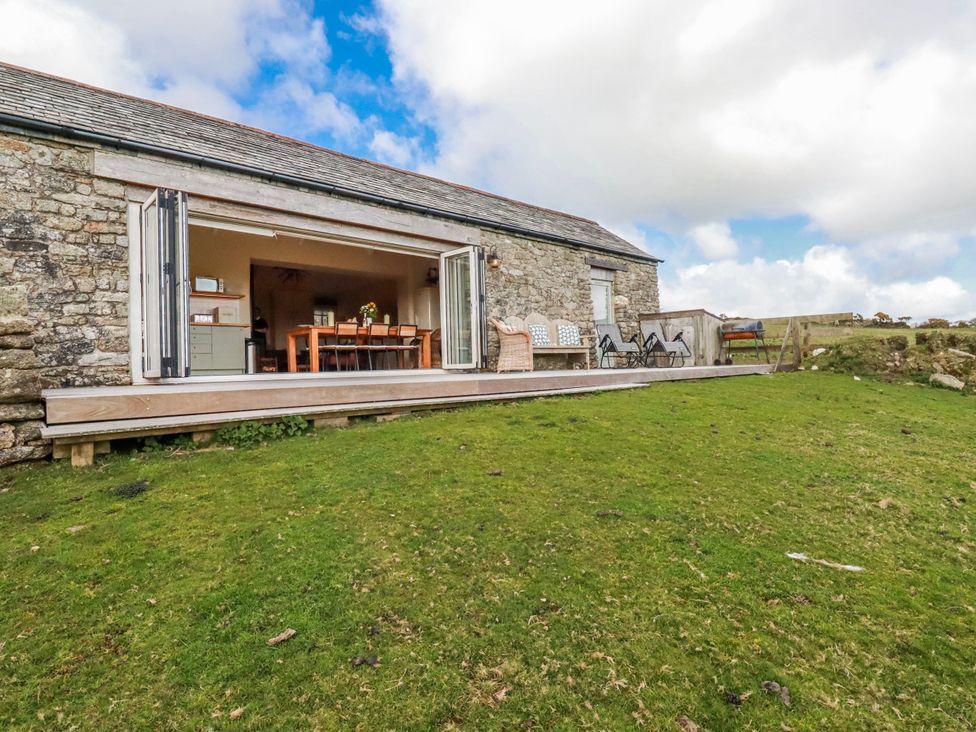 A dining area with open doors and grass outside at Roughtor Barn Poldue near Camelford