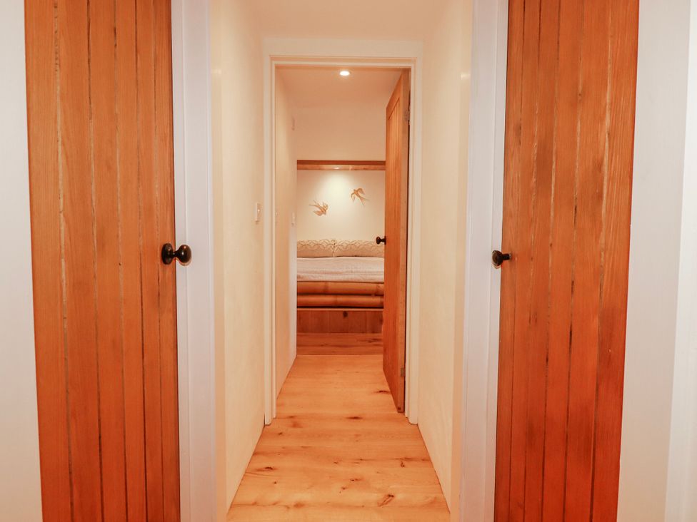 A hallway with wooden doors and a bed visible at Logan Barn in Poldue near Camelford