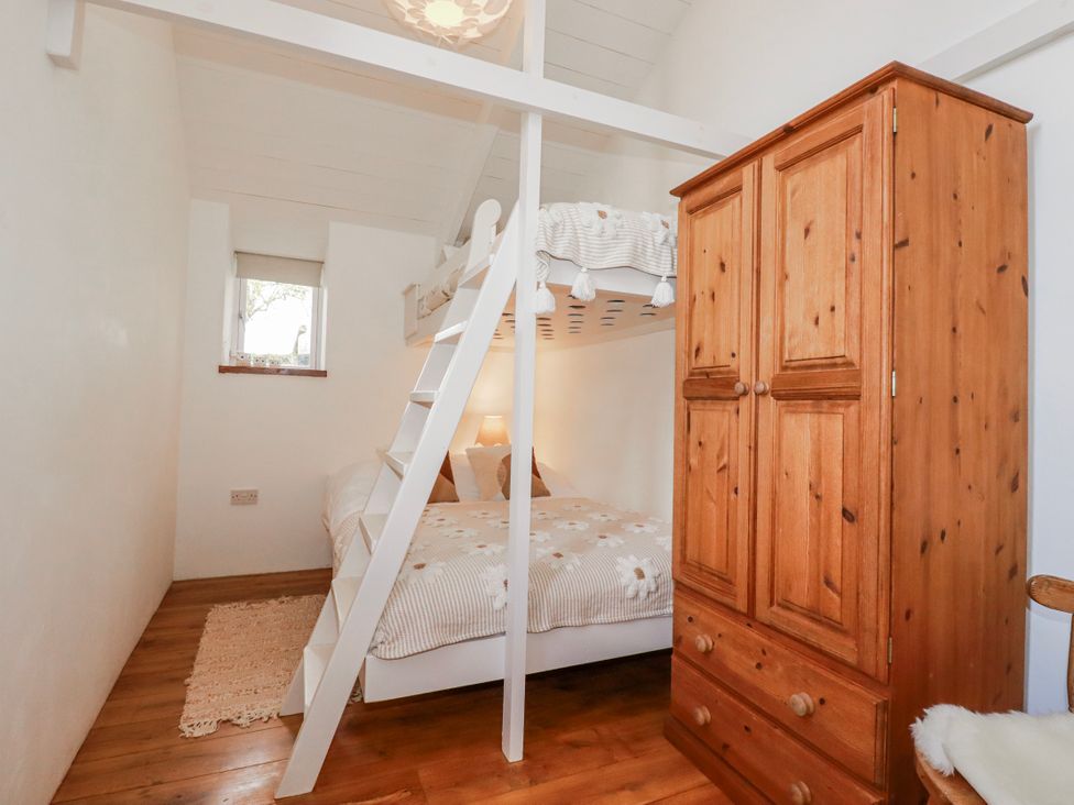 A bedroom with a bunk bed and a double bed at Logan Barn in Poldue near Camelford