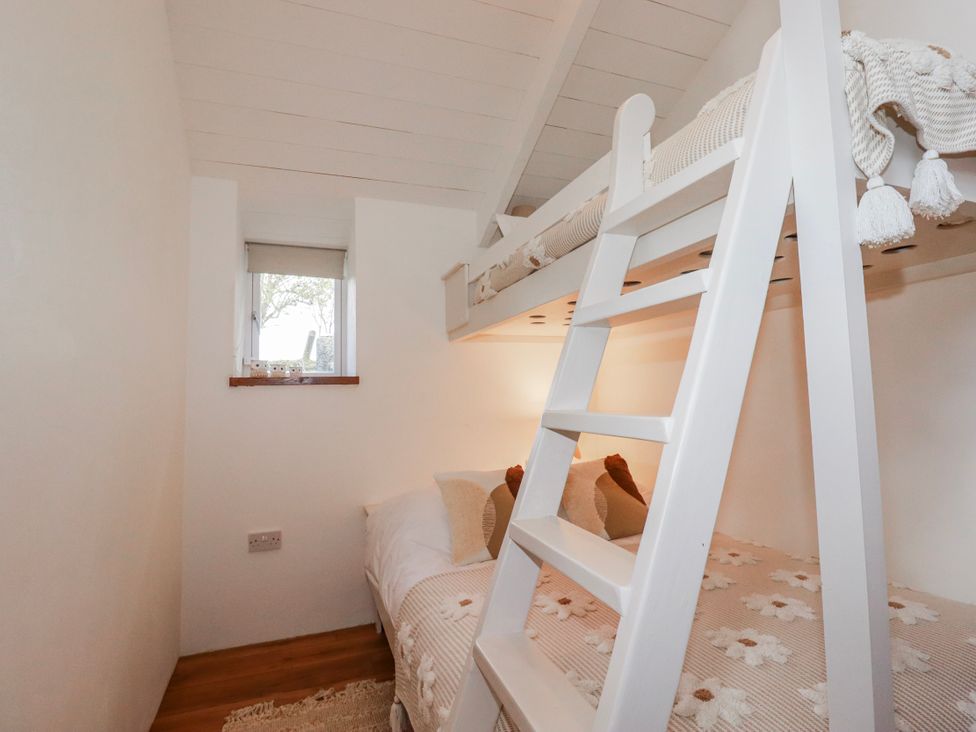 A bedroom with a bunk bed and a window at Logan Barn in Poldue near Camelford