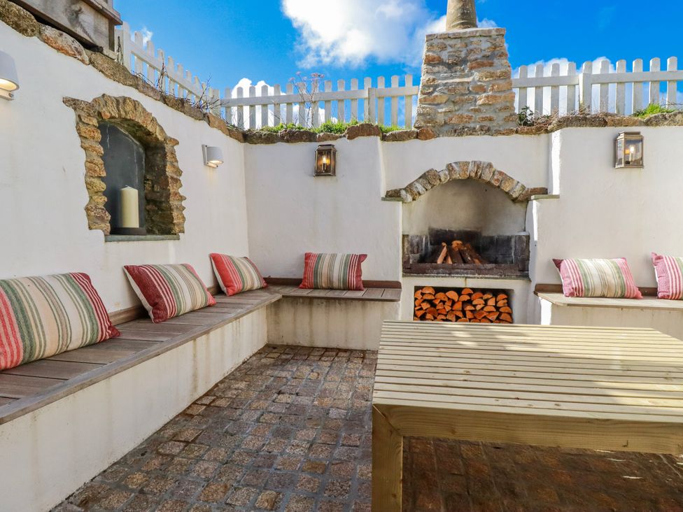 An outdoor seating area with a fireplace and a table at Logan Barn, Poldue near Camelford