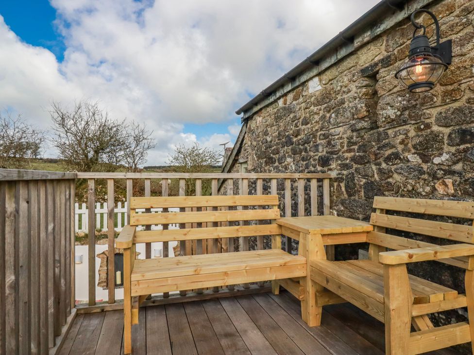 An outdoor seating area with wooden furniture at Logan Barn, Poldue near Camelford