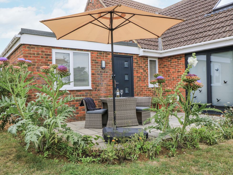 An outdoor seating area with a table and chairs under an umbrella at The West Wing in Potterne