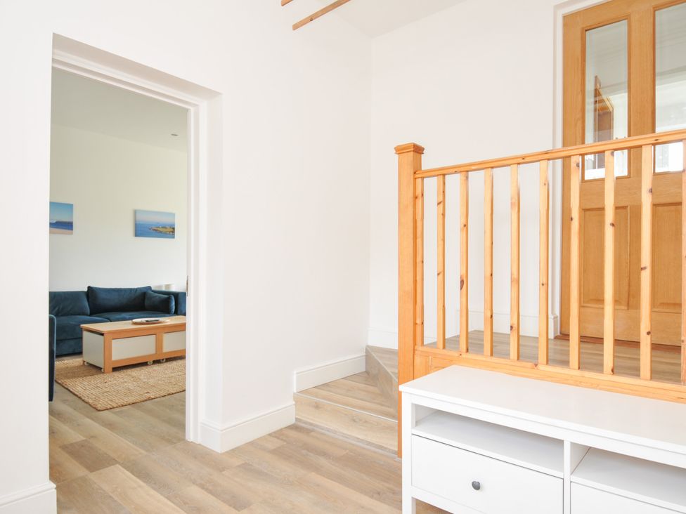 A hallway leading to a living room with a sofa and coffee table at Seaworthy in Daymer Bay