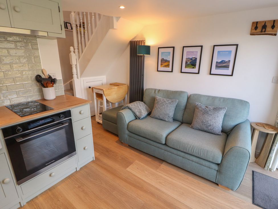 A living room with a sofa and kitchen area at Wren's Nest in Thornthwaite near Braithwaite