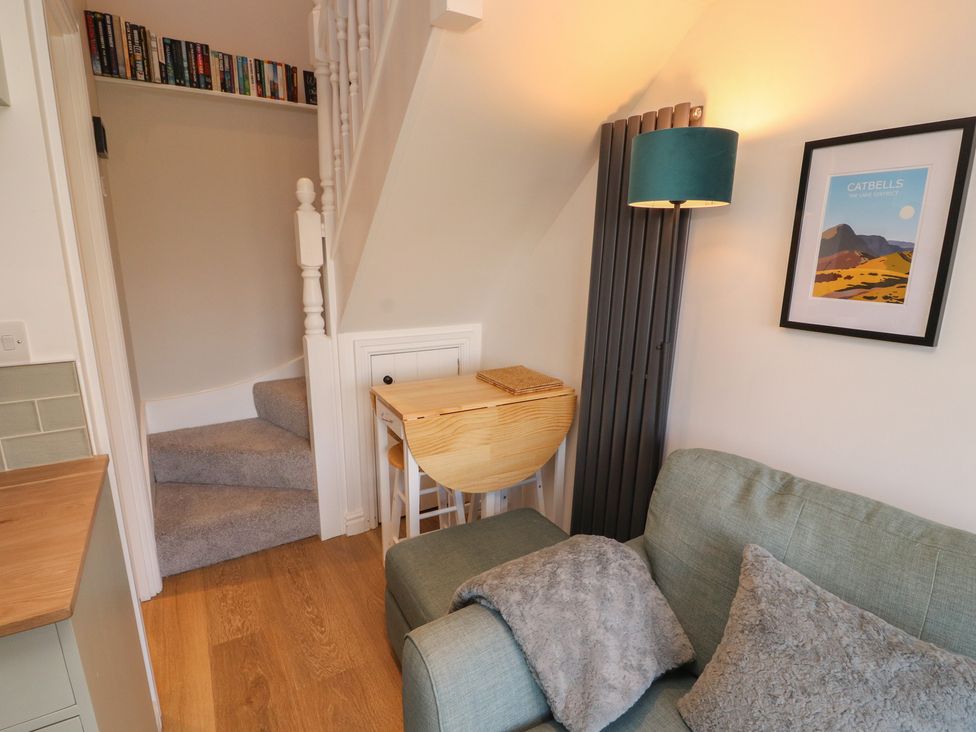 A living room with a sofa and a staircase at Wren's Nest in Thornthwaite near Braithwaite