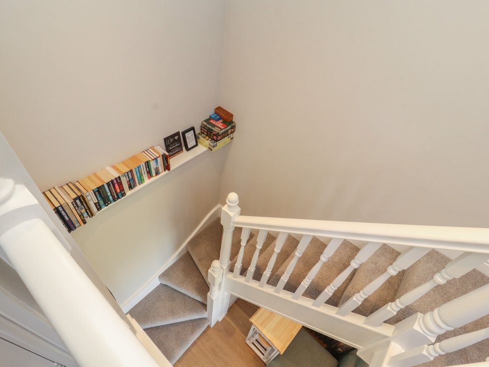 A staircase with a bookshelf and table at Wren's Nest Thornthwaite near Braithwaite