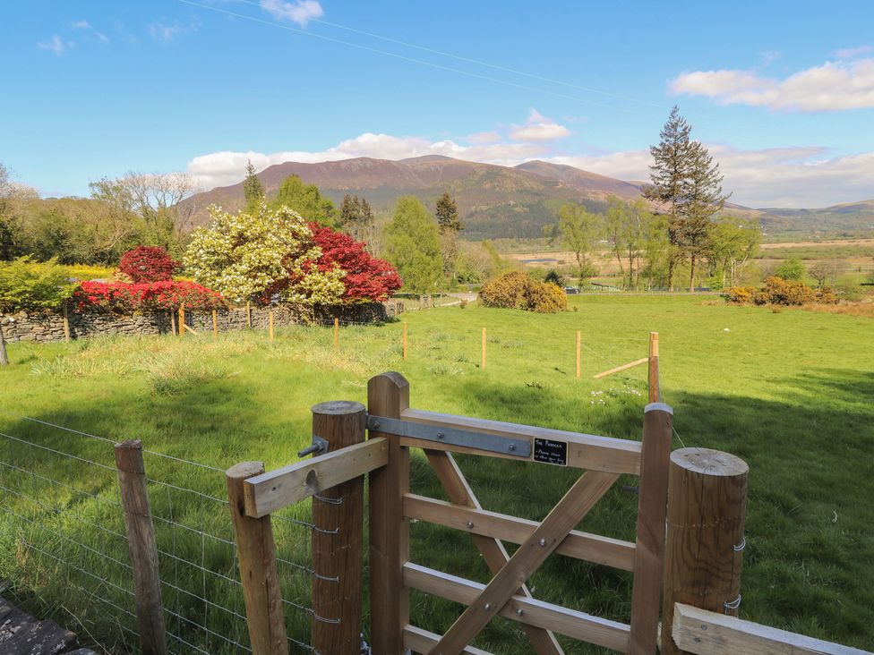 A field with a wooden gate and trees at Wren's Nest in Thornthwaite near Braithwaite