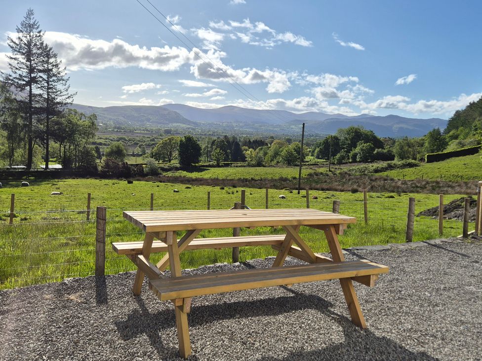 A picnic table surrounded by trees and mountains at Wren's Nest Thornthwaite near Braithwaite