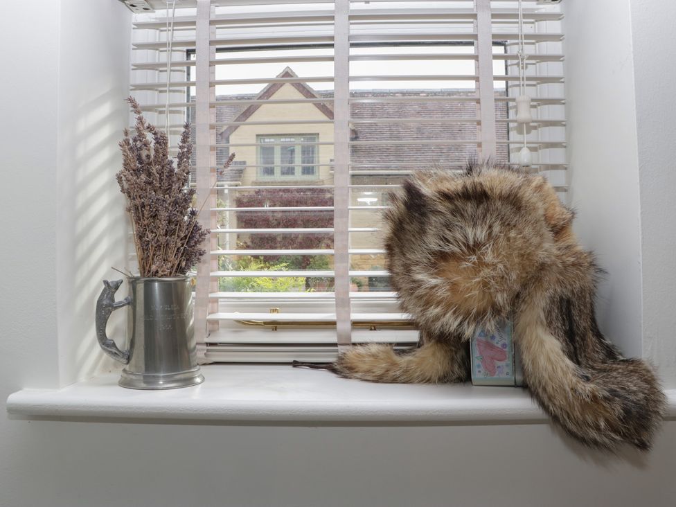 A window with a metal cup and a fur hat at Cottage - 1 bedroom in Broadway