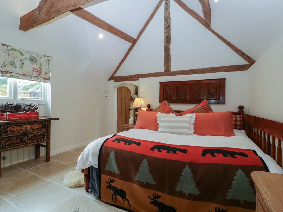 A bedroom with a bed and wooden furniture at Cottage - 1 bedroom in Broadway