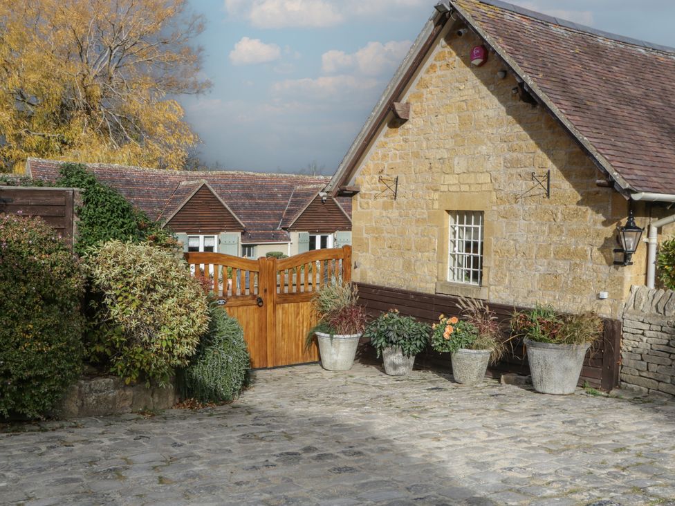 A stone house with a wooden gate and plant pots at Cottage - 1 bedroom Broadway