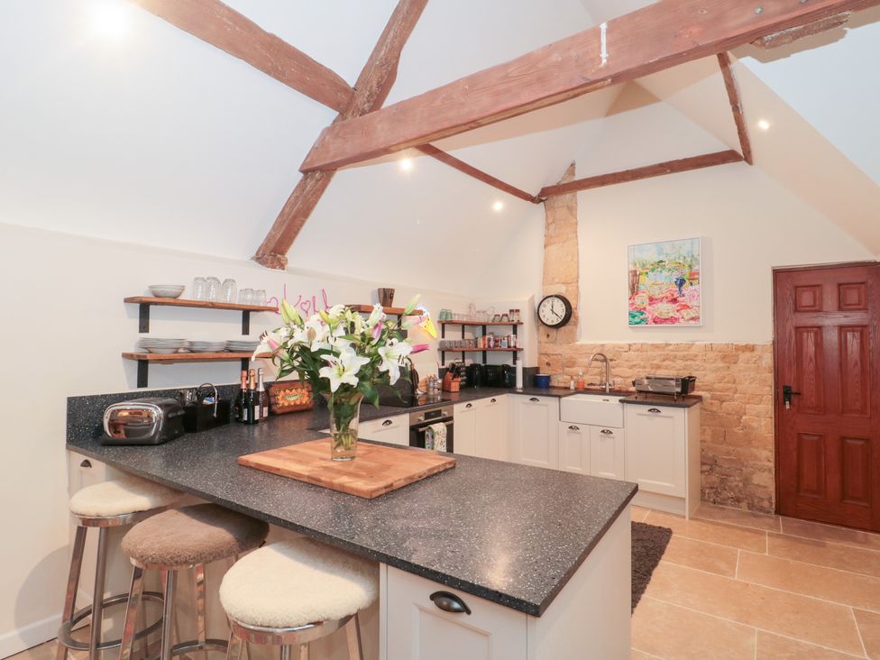 A kitchen with a countertop and bar stools at Garden Cottage in Saintbury near Broadway