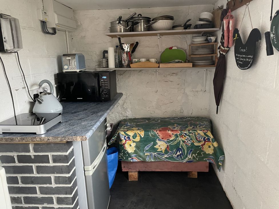 A kitchen with a stove, kettle, microwave, and shelf at Ty Hir at Blaenbrynich Farm Libanus near Sennybridge