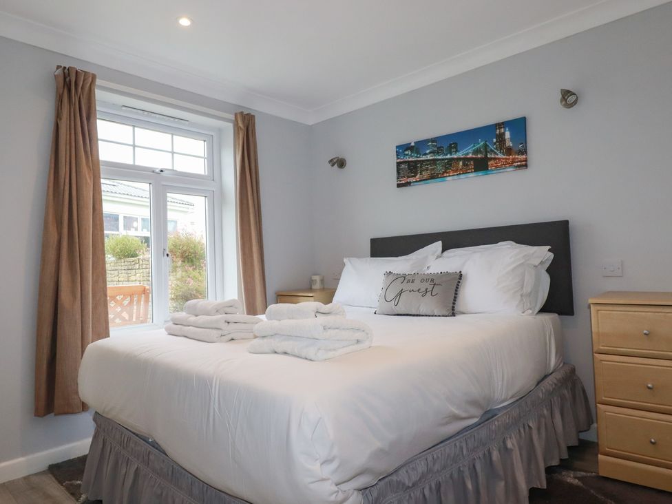 A bedroom with a bed and nightstand at Satinwood in White Cross near Newquay