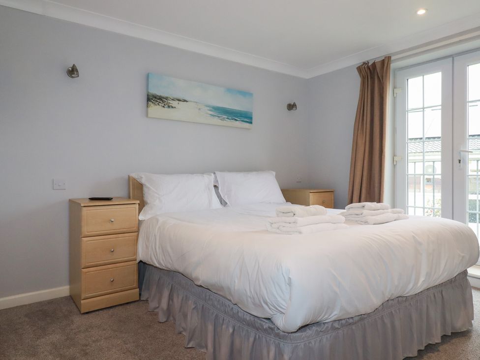 A bedroom with a bed and nightstands at Satinwood in White Cross near Newquay