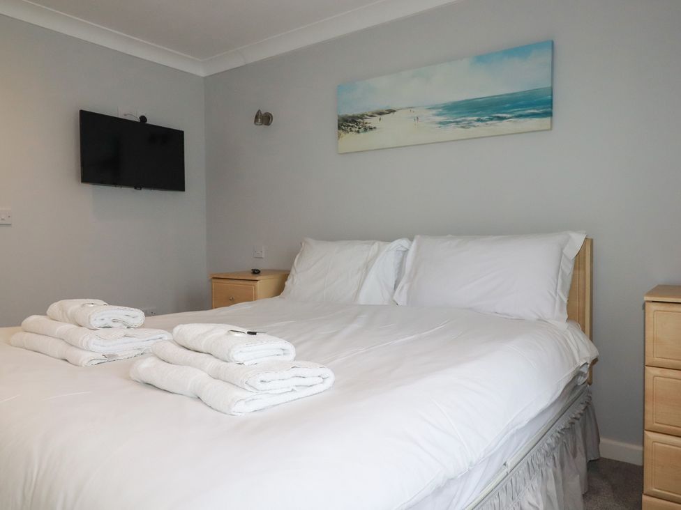 A bedroom with a bed, television, and towels at Satinwood White Cross near Newquay