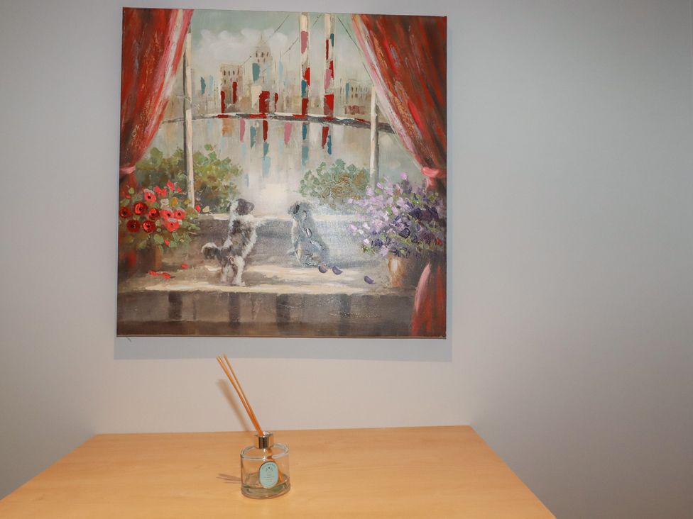 A painting of dogs and flowers above a table at Satinwood in White Cross near Newquay