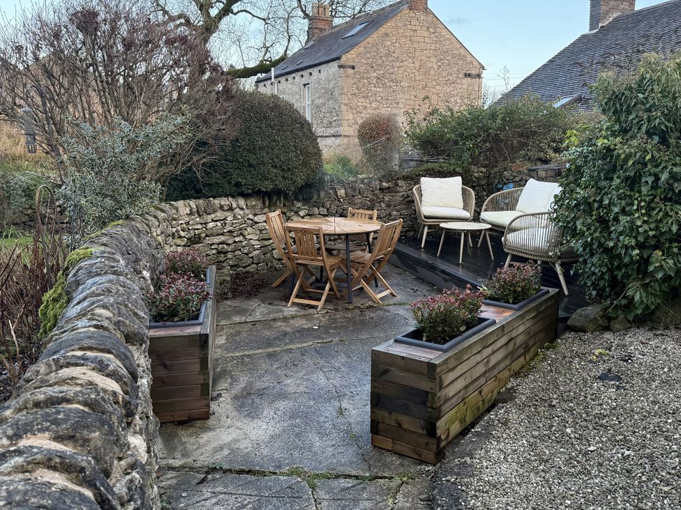 A garden with a wooden table and chairs at The Warren in Middleton near Wirksworth