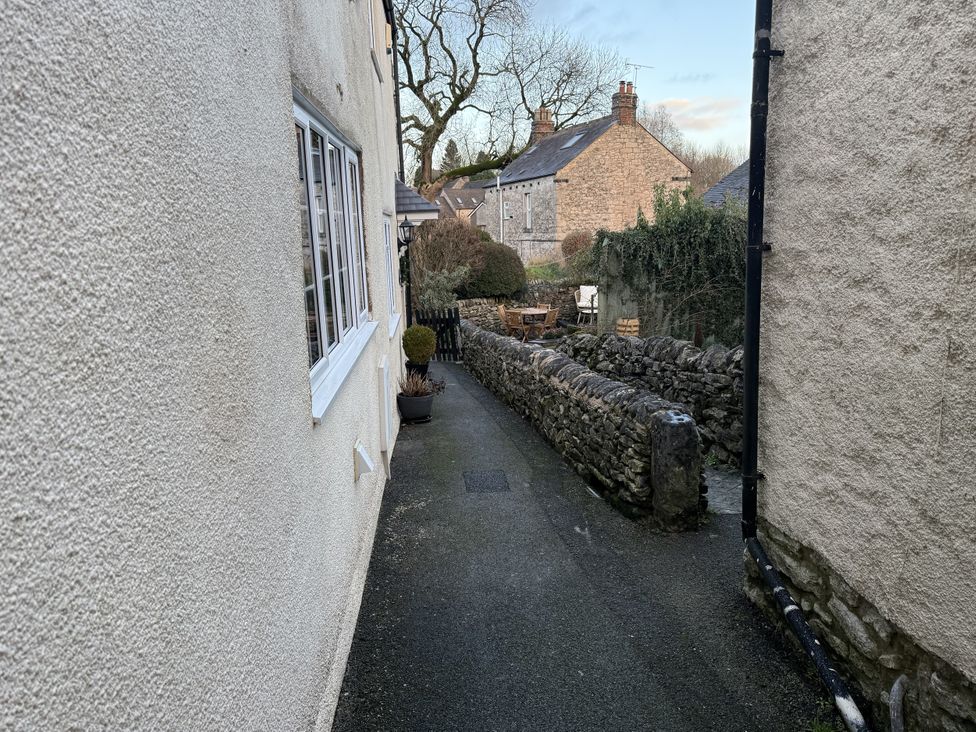 A pathway beside a house with a stone wall and furniture at The Warren in Middleton near Wirksworth