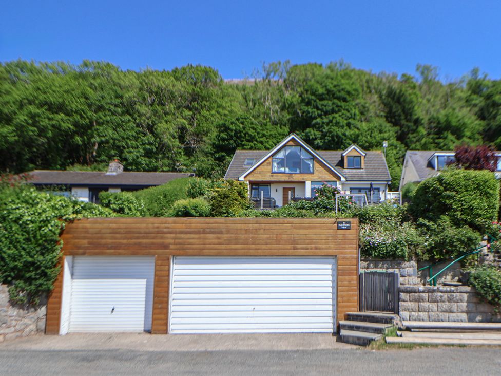 A house with a wooden garage door and bushes around at Buzzards View in Dyserth