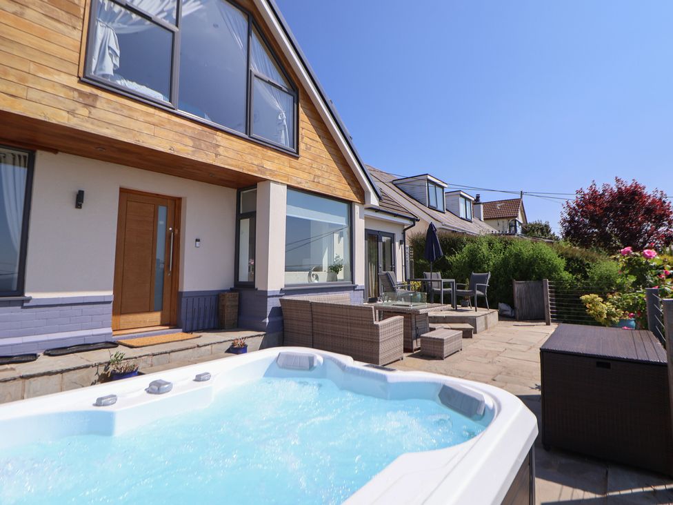 An outdoor patio with a hot tub chairs tables and plants outside a modern house at Buzzards View in Dyserth