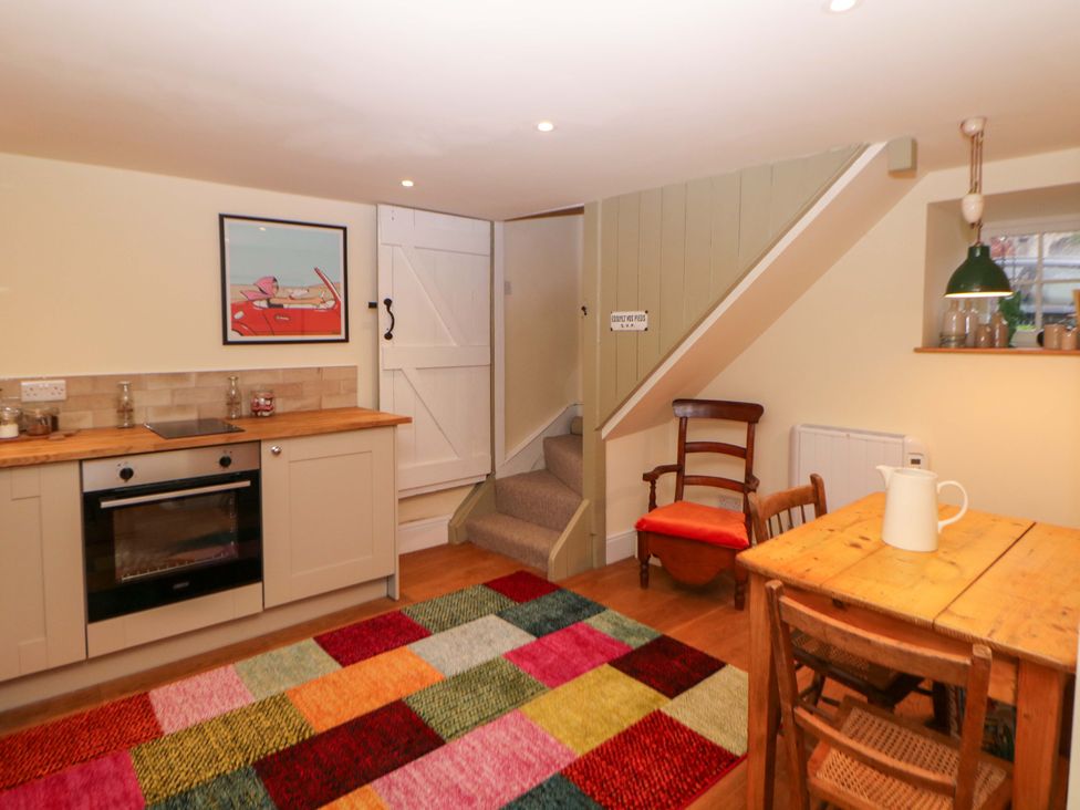 A kitchen with counter, table, chairs, and stairs at Laneside Barn Calver